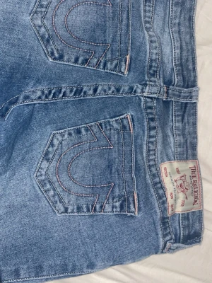 True Religion ljusblå jeans - Säljer ett par true religion jeans, rosa sömmar, lågmidjade jeans. Jeansen heter "Joey" bootcut jeans !! W29/M kan passa S också