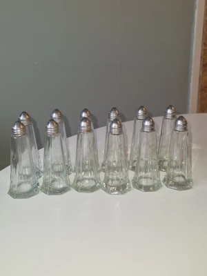 Kryddburkar  - Säljer ett set med 12st små kryddburkar i glas. Perfekta till middagsbjudningar eller café. Klassisk design som passar in i de flesta kök.  Lite rost förekommer pga svårdiskade- men inget farligt och inget som syns när locken sitter på. Höjd på burkarna- 9cm,  Höjd med lock- 11cm.  