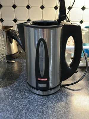 Elektrisk vattenkokare Menuett - Säljer en elektrisk vattenkokare från Menuett i rostfritt stål med svarta plastdetaljer. Den har ett genomskinligt fönster för vattennivå och ett ergonomiskt handtag. Perfekt för att snabbt koka vatten till te eller kaffe.