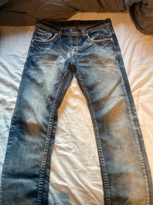Smog jeans straight - Säljer ett par blå jeans från Smog med snygga slitningar och tvättade detaljer. Klassisk femficksmodell med raka ben och kontrastsömmar. 