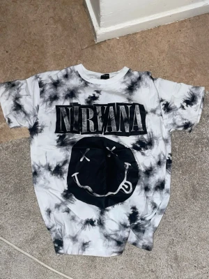 Nirvana tie-dye t-shirt & blå skate t-shirt - Två t-shirts: En vit och svart tie-dye Nirvana t-shirt med stort tryck framtill och korta ärmar. En marinblå t-shirt från a.fantasy med skate-tryck och text, också med korta ärmar. Båda i mjuk bomull och perfekt för en avslappnad stil. för 10-11 år kläder alla t-shirtserna kostar 150 kr om ni vill köpa
