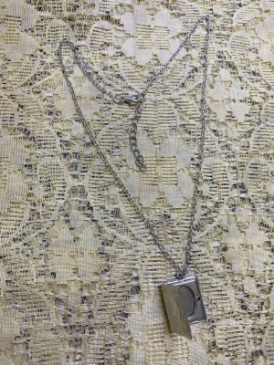 Magic Bok / Photoram Halsband  - Snyggt silverfärgat halsband med en fyrkantig medaljong som har fina graverade detaljer. Kedjan är tunn och har ett klassiskt spänne. Medaljongen kan öppnas och har en retrovibe som passar till många olika stilar.