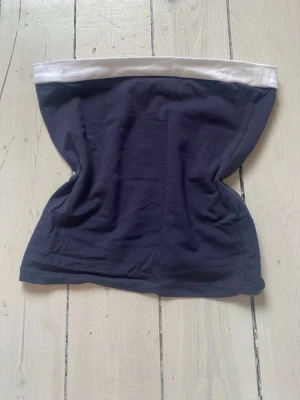 Mörkblå tubtopp från Subdued - Snygg mörkblå tubtopp från Subdued med vit kant upptill. Enkel och stilren design som passar perfekt till sommaren. Gjord i mjukt bomullsmaterial för en bekväm känsla. Perfekt att matcha med jeans eller kjol.