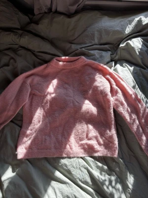 Ljusrosa stickad tröja - Mysig ljusrosa stickad tröja med rund hals och långa ärmar. Tröjan har en avslappnad passform och är tillverkad i ett mjukt, fluffigt material som känns skönt mot huden. Perfekt för dig som gillar en enkel men söt stil. Storlek m men passar mig som är xs-s, märke key west