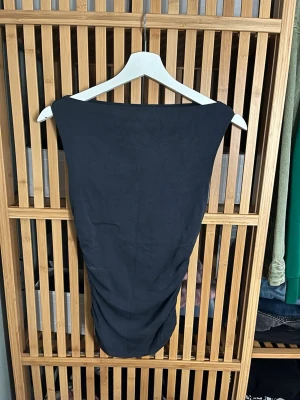 Svart ärmlös topp från BikBok - Snygg svart ärmlös topp från BikBok i stretchigt bomullsmaterial. Modellen är tight och croppad med bred halsringning, perfekt att styla med höga jeans eller kjol. (lite nopprig men syns knappt)