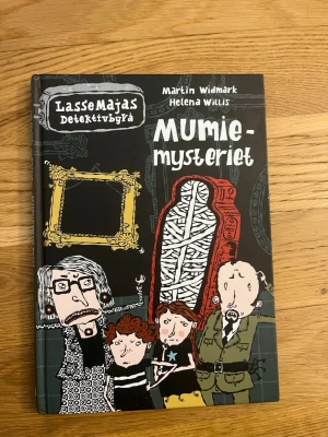 LasseMajas Detektivbyrå: Mumiemysteriet - LasseMajas Detektivbyrå: Mumiemysteriet av Martin Widmark och Helena Willis är en illustrerad kapitelbok med svart, röd och vit framsida. Boken har hårda pärmar och bjuder på ett spännande mysterium där Lasse och Maja undersöker en mumie på museet.