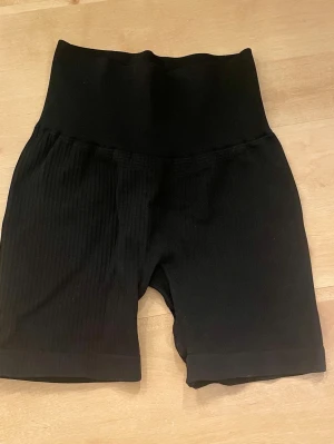 Svarta ribbade cykelshorts - Säljer ett par svarta ribbade cykelshorts. De är stretchiga och sitter tight, perfekta för en sportig look eller till vardags. Tillverkade i Italien och har en bekväm passform.
