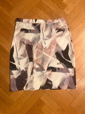 Mönstrad kortkjol från Lost Ink - Säljer en kortkjol från Lost Ink med abstrakt mönster i vitt, svart, lila och beige. Kjolen har en rak passform och är tillverkad i ett mjukt syntetmaterial som känns bekvämt mot huden. Perfekt för dig som vill sticka ut med en unik look.Skriv gärna för mått! 💕