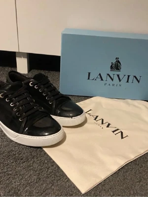 Svarta Lanvin sneakers i läder - Snygga svarta sneakers från Lanvin med vita sulor och svarta snören, Säljer dessa otroligt fina lanvins i super skick skorna är i storlek uk 6 vilket motsvarar 40-41 män passar avän 42. Allt på bild medföljer. Hör av er vid funderingar 😁.       /Tonanresell