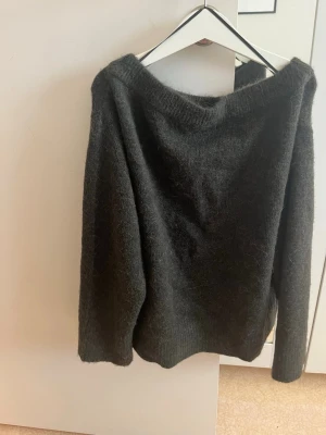 Mörkgrön stickad tröja - Helt ny andvänd en gång En enkel och stilren mörkgrön stickad tröja med rund hals och långa ärmar. Tröjan är gjord i ett mjukt och fluffigt material som känns skönt mot huden. Perfekt att slänga på sig när det är kyligt ute.
