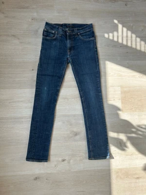 Blåa Nudie Thin Finn Jeans W28 L32 - Fina Nudie Jeans i blå färg. Jeansen är i mycket bra skick och sparsamt använda.  Äkta som allt annat jag säljer! ✅  Storlek: W28 L32 Skick: Mycket Bra Skick Färg: Blå Märke: Nudie Modell: Jeans   Hör gärna av dig vid frågor så svarar jag så fort jag kan! 😁   (SKU - 2)