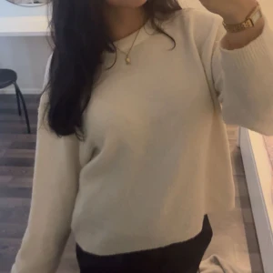 Beige stickad tröja i oversize - Mysig vit stickad tröja i oversize-modell med rund halsringning och långa ärmar. Perfekt för lager på lager och enkel att matcha med olika stilar. Tröjan har en mjuk och slät yta som ger en avslappnad look.