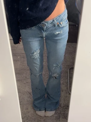 Ljusblå lowrise bootcut jeans egna gjorda hål - Säljer ett par ljusblåa lowrise bootcut jeans från junkyard med egna gjorda hål i storlek XS kostade 700kr köpta därav priset