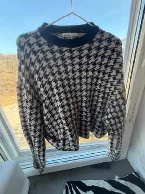 Svartvit stickad tröja från Mango - Säljer en svartvit stickad tröja från Mango med klassiskt hundtandsmönster. Tröjan har rund halsringning med svart ribbad kant och långa ärmar. Perfekt för dig som gillar tidlösa mönster och vill ha en mysig stickad tröja till garderoben.