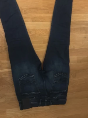 Mörkblå replay jeans  - Snygga mörkblå jeans med slim fit passform och klassiska femficksdetaljer. Jeansen har lätt slitna partier framtill och bakfickor med dekorativa sömmar. Perfekta till en avslappnad stil.