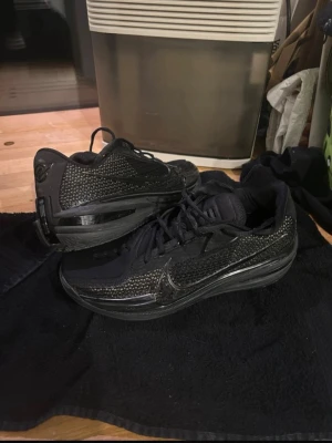 Gt cut 1 ” Tripple Black” - Säljer ett par svarta Nike basketskor med snygg textur på ovandelen och diskret Nike-logga på sidan. Skorna har snörning och en robust sula som passar perfekt för både träning och streetwear. Materialet är en mix av mesh och syntet för bra andningsförmåga.
