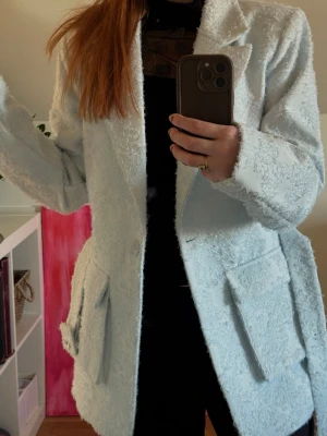 Ljusblå kavaj med bälte - Trendig ljusblå oversized kavaj med markerade axlar och stora fickor framtill. Använd vid endast ett tillfälle. Från NA-KD i storlek Small men passar även M.