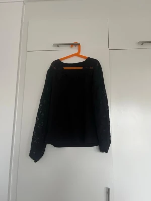 Svart tröja med spetsärmar - Snygg svart blus med transparenta spetsärmar och rund halsringning. Blusen har en rak passform och är tillverkad i ett lätt tyg som ger en elegant look. Perfekt för dig som gillar stilrena detaljer och vill ha något extra till outfiten. Köpt på Vinted men passade inte mig. Storlek XL men passar en L mer 🩷