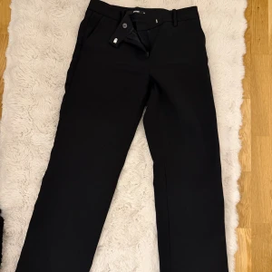 Svarta kostymbyxor med raka ben - Snygga svarta kostymbyxor från BikBok med klassisk rak passform och pressveck. Användt ungefär 2 gånger.