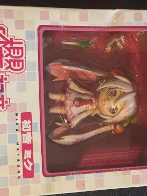 Sakura Miku Hatsune figur - Supergullig Sakura Miku Hatsune figur i rosa och vitt med körsbärsdetaljer i håret. Perfekt för cosplay eller som samlarpryl. Kommer i originalförpackning och har utbytbara tillbehör. Material: plast.