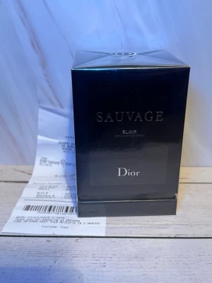 Dior Sauvage Elixir parfym 100ml - Dior Sauvage Elixir är en exklusiv parfym i en elegant, mörkblå fyrkantig kartong med silverdetaljer. Förpackningen har en lyxig känsla och tydlig Dior-logga framtill. Perfekt för dig som gillar kraftfulla och unika dofter.