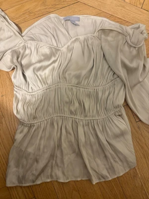 Offshoulder topp - Snygg offshoulder topp/blus i asball silvrig/beige färg!!!🥰 Passar till allt❣️Vill tillägga att den är stretchig och passar alla storlekar till M