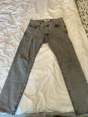 Woodbird jeans - Grå Jeans från Woodbird, rak passform och fem fickor. Jeansen har en vintage look med subtila slitningar och är tillverkade i 100% bomull. Perfekta för en avslappnad och stilren outfit.