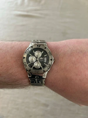 Vintage Herrklocka Chrono Diver 36mm - Bretling Chronometer Automatic med boett och armband i stål. Urtavlan är svart med tre cirklar och datumvisning. Klockan har en vridbar bezel. Baksidan är märkt "STAINLESS STEEL BACK WATER RESISTANT 3ATM. Trippel A Replik@. Okänd funktion. Fint använt skick enligt bilder.