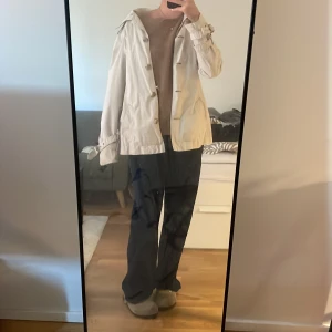 Beige trenchcoat med knappar - Säljer en beige trenchcoat med knappar och bälte vid ärmsluten. Jackan har en klassisk design med normal passform och långa ärmar.  för vår och höst! Står XL, men sitter som M! Är 174cm och har vanligtvis M. 