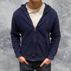 Ralph Lauren zip hoodie blå - •Ralph Lauren Full-Zip Hoodie Navyblå. Skick: 7/10,  Storlek: L 14/16 yrs ungdom = XS~. •Mått, axel-neråt: 54 cm, bredd: 46 cm. Modell: 173 cm, 63 kg. Sitter för litet på modell! Authentic: ✅. Hör av dig vid frågor eller funderingar 
