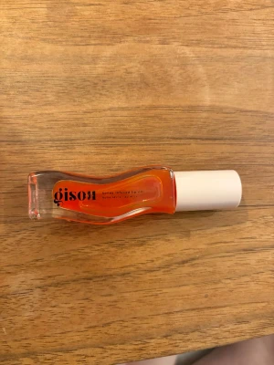 Gisou honey infused lip oil mango passion punch - Säljer ett läppbalsam i form av en olja från Gisou. Färgen är lätt tint av orange med smak av mango passion och förpackningen är i genomskinligt glas med vit kork. Oljan är honey infused och ger glansiga, återfuktade läppar. Perfekt för dig som gillar en fräsch och naturlig look.