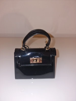 Svart minihandväska med guldkedja - Snygg svart minihandväska med guldkedja.  Stilren och trendig accessoar som lyfter din outfit.