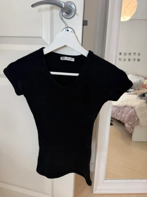 Svart v-ringad topp från Zara - En svart, tight v-ringad topp från Zara med korta ärmar. Mjuk och stretchig i materialet💕
