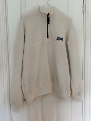  fleece från Urban Tears - Mysig fleece med halv dragkedja från Urban Tears. Tröjan har hög krage, ribbade muddar och en liten patch på bröstet. Perfekt för lager-på-lager och chill dagar. Materialet är mjukt och värmande.