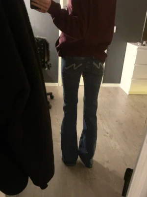 Blå bootcut jeans från Nelly - Säljer ett par klassiska blå bootcut jeans från Nelly med snygga broderade detaljer på bakfickorna. Jeansen har normal midja och utsvängda ben, perfekt för en avslappnad och trendig look. 💓