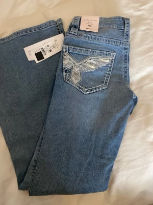 Ljusblå bootcut jeans med paljettdetaljer från Gina tricot  - Snygga ljusblå bootcut jeans från ginatricot med coola silverfärgade paljettdetaljer på bakfickorna. Säljer då det är i fel storlek! Orginalpris är 349kr💕kontakta för fler bilder och pris går att diskutera🥰