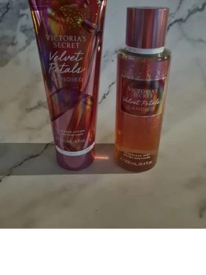 Victoria's Secret Velvet Petals Candied - Säljer ett set med Velvet Petals Candied från Victoria's Secret. Innehåller en body mist (250 ml) och en body lotion (236 ml). Båda har en glansig rosa och guldig design med inslag av lila. Doften har inslag av karamell och blommiga toner. Helt nytt och oanvänt 