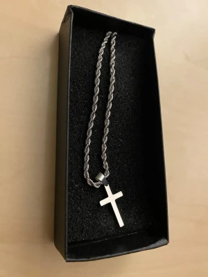 Stilrent ropechain halsband 50cm 5mm med kors rostfritt stål - Snyggt halsband i silverfärg med tvinnad kedja och ett stilrent kors som hänge. Perfekt accessoar för dig som gillar minimalistisk design. Levereras i svart ask.