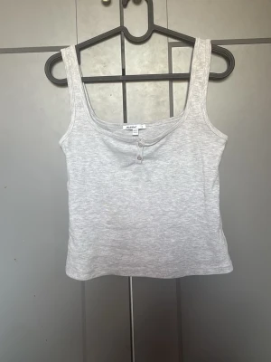 Ljusgrå ribbad linnetopp Subdued - Säljer en ljusgrå ribbad linnetopp från Subdued. Toppen har breda axelband, rundad urringning och två små knappar framtill. Perfekt till jeans eller kjol för en enkel och chill look.