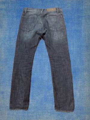 Tiger of Sweden jeans - Snygga mörkblå jeans från Tiger of Sweden med raka ben och klassisk femficksmodell. Jeansen har slitningar och tvättade detaljer för en cool look. Tillverkade i denim med en skön passform och läderpatch bak i midjan. Storlek 33/32