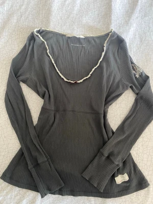 Grå babydoll tröja - Supersnygg grå ribbad babydoll topp från Odd Molly med lång ärm och v-ringad hals med vit spetsdetalj och rosett. Nästan aldrig använd så är i mycket fint skick! Storlek S-M!💗