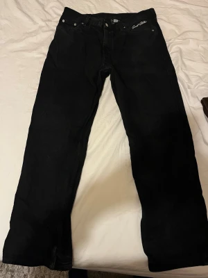 Svarta raka jeans sweet  - Säljer ett par svarta jeans från sweet med rak passform och klassisk femficksdesign. Jeansen har diskret logga på fickan fram samt patch bak i midjan. Perfekta för dig som gillar en enkel och stilren look.