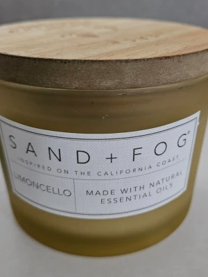 Doftljus Sand + Fog Limoncello - Säljer ett gult doftljus från Sand + Fog med doften Limoncello. Ljuset kommer i en frostad glasburk med ett snyggt lock i trä där det står 'PEACE' och har ett ingraverat bladmönster. Tillverkat med naturliga eteriska oljor.