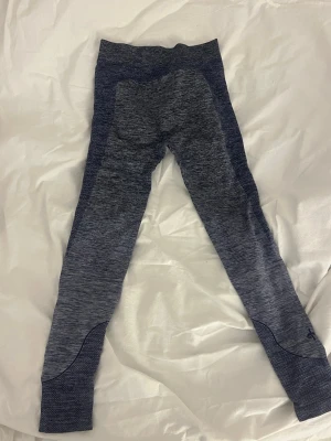 Mörkblå sömlösa leggings - Snygga mörkblå sömlösa leggings med melerad effekt och hög midja. Materialet är stretchigt och andas, perfekt för träning eller chill. Diskret logga vid ankeln och förstärkta partier vid knä och benslut för extra komfort.