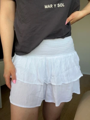 Vit volangkjol med resårmidja från Walmart, storlek 8 (S) - Vit kjol med bred smock i midjan och dubbla volanglager, köpt på Walmart i Australien. 100% viskos. Aldrig använd.