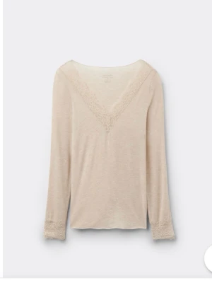 Intimissimi topp - Snygg beige långärmad topp med v-ringning och spetsdetaljer både vid halsringningen och ärmsluten. Perfekt att styla till jeans eller kjol för en enkel men chic look.