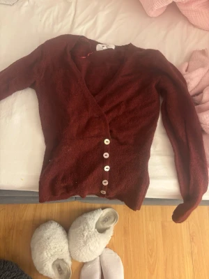 Vinröd kofta från Gina Tricot XS - Mysig vinröd kofta från Gina Tricot i alpackablandning. Koftan har v-ringning, långa ärmar och vita knappar framtill. Figurnära passform och mjukt material som känns lyxigt och skönt mot huden.