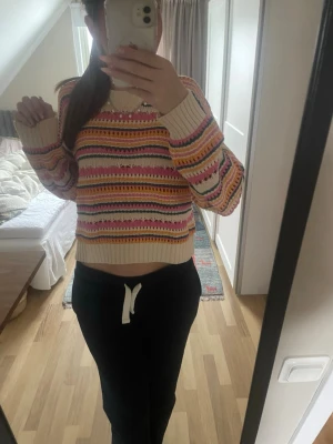 Söt tröja från Zara - Säljer en stickad cropped tröja med färgglada ränder i rosa, gul, grön och vit. Tröjan har rund hals, långa ärmar och ribbade muddar. Materialet är mjukt och tröjan har ett hålmönster som ger en cool och trendig look. Knappt använd 