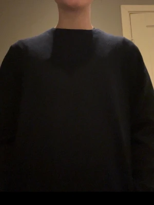 Mörkblå stickad tröja från Uniqlo - Säljer en stilren mörkblå stickad tröja från Uniqlo i storlek S. Tröjan har rund halsringning och långa ärmar, perfekt för lager-på-lager under kyliga dagar. Enkel design utan mönster eller detaljer, vilket gör den lätt att matcha med olika outfits.