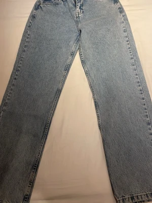 Ljusblåa raka jeans - Säljer ett par ljusblåa jeans med rak passform och hög midja. Jeansen har klassiska fem fickor och är tillverkade i kraftigt denimtyg. Perfekta för en avslappnad och trendig look.